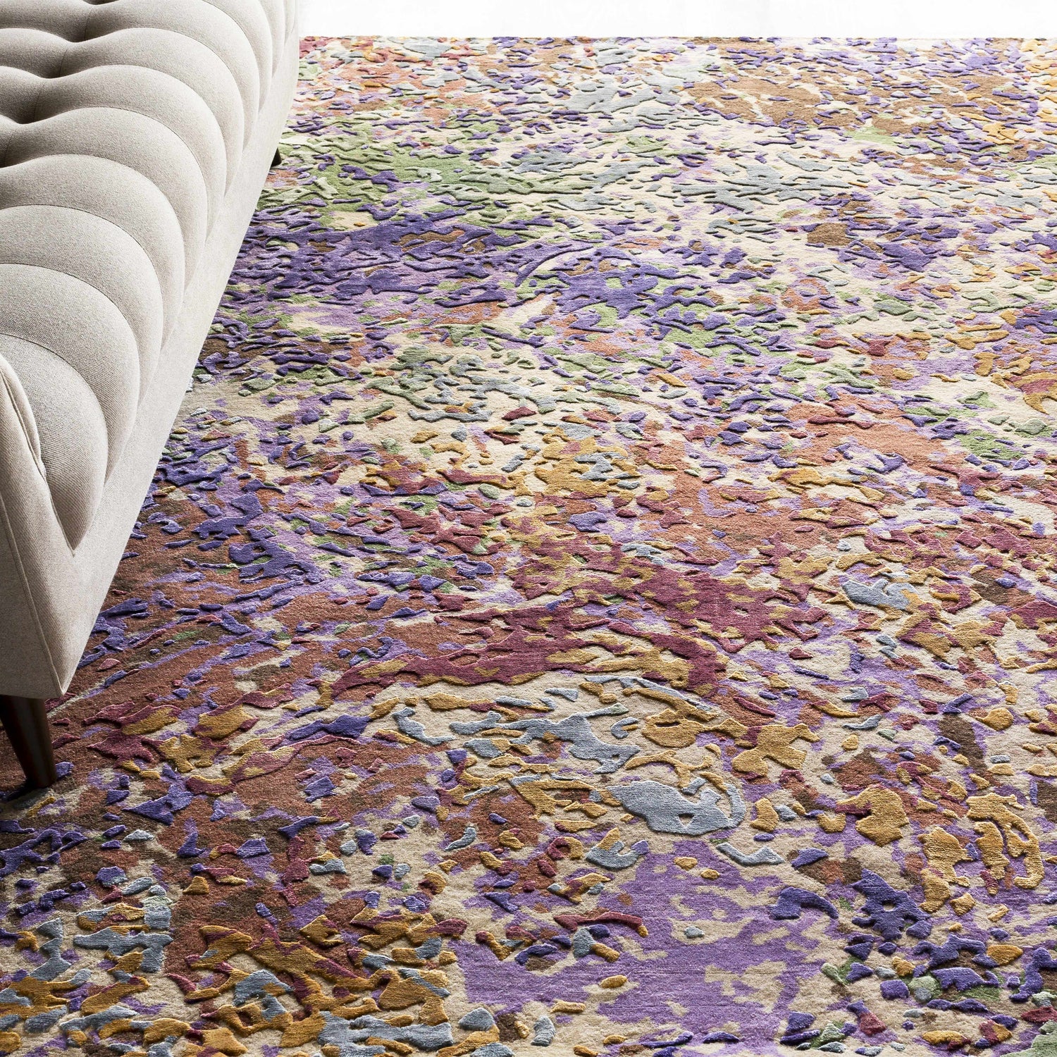 Contemporary living room with a tufted sofa and the Bronxville Area Rug in dark brown, lavender, lilac, olive, and peach. Styleshot
