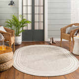 Cozy porch scene with a beige oval Burradoo Bordered Area Rug, wicker chairs, and wood floors. Relaxing, neutral color palette. Roomscene-Oval