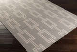 Close-up of the Brundidge Area Carpet. Gray wool rug with an ivory geometric chain-link pattern. Contemporary style. Corner