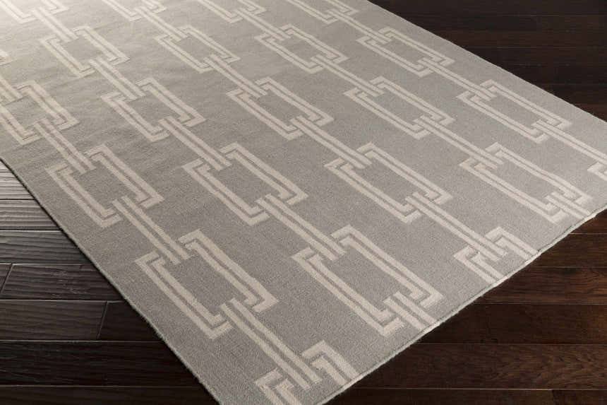 Close-up of the Brundidge Area Carpet. Gray wool rug with an ivory geometric chain-link pattern. Contemporary style. Corner