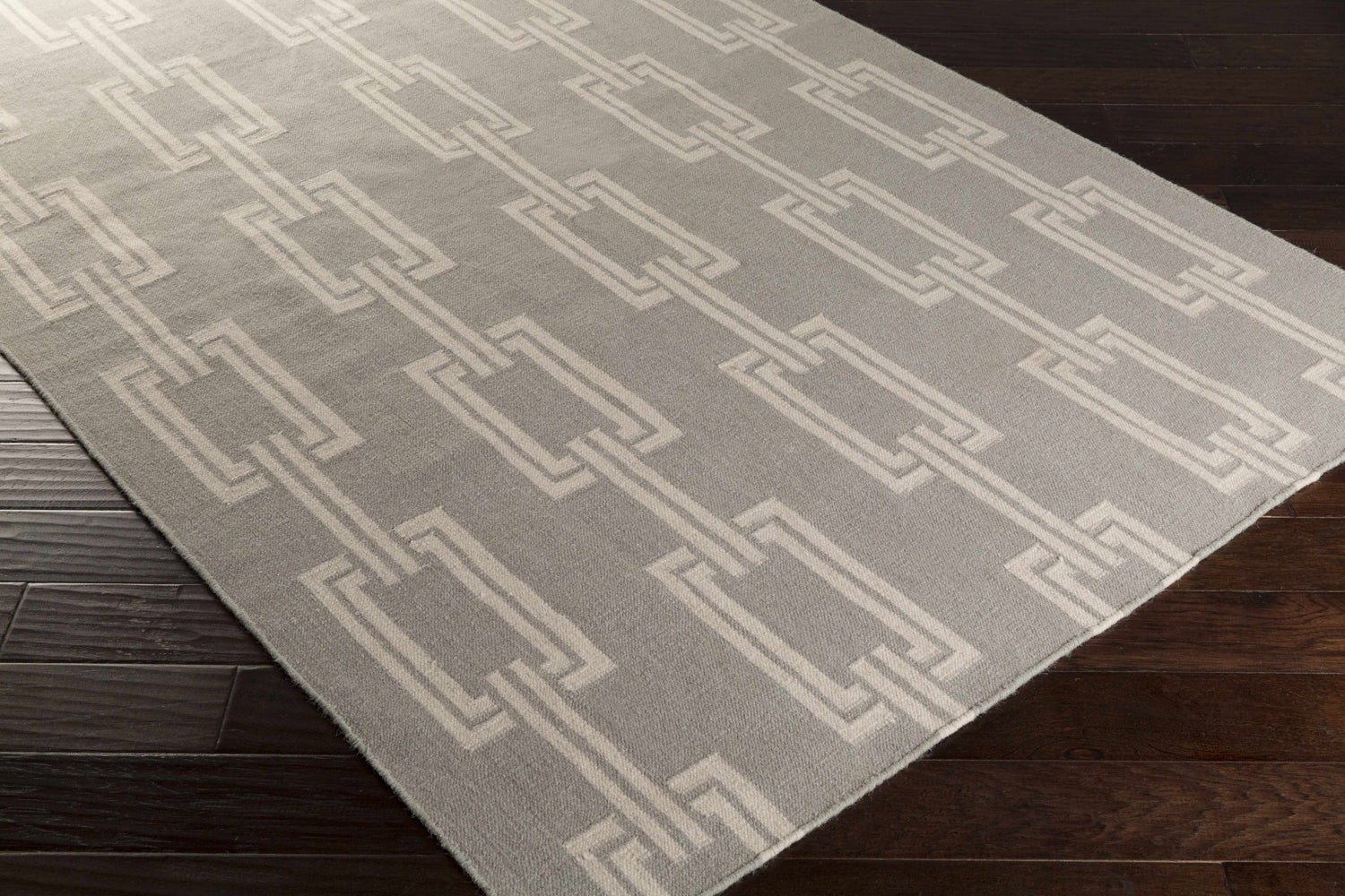 Close-up of the Brundidge Area Carpet. Gray wool rug with an ivory geometric chain-link pattern. Contemporary style. Corner