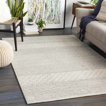 Living room scene with a Basinger Tufted Maroc Wool Rug in gray and ivory, complementing the neutral sofa and dark wood floors. Roomscene-Rectangle