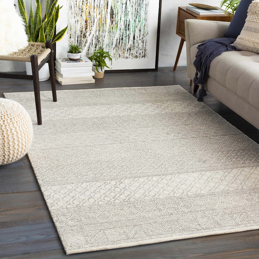 Living room scene with a Basinger Tufted Maroc Wool Rug in gray and ivory, complementing the neutral sofa and dark wood floors. Roomscene-Rectangle