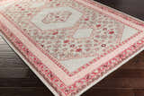 Angled view of the Bethesda Area Rug in burgundy, dusty pink, and gray on a dark wood floor. Hand-knotted wool rug. Corner