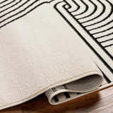 Close up of the Buana Area Rug showing its beige and black geometric design and texture. Fold