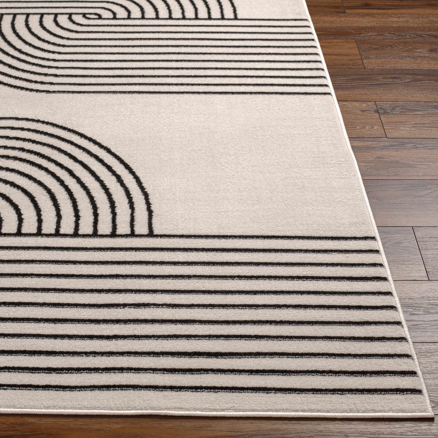 Close-up of the Buana Area Rug. Beige rug with a geometric black line pattern. Mid-Century Modern style. Front