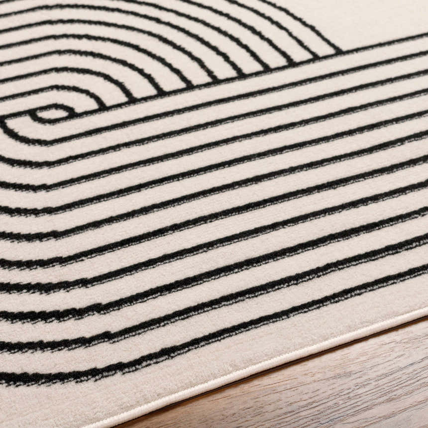 Close-up of the Buana Area Rug. Beige rug with a black geometric pattern of lines and curves. Texture