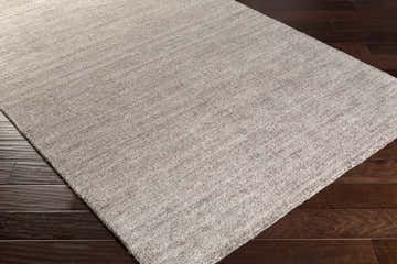 Close-up of the gray Buskirk Area Rug showing its hand-loomed texture and subtle contemporary design on dark wood flooring. Corner