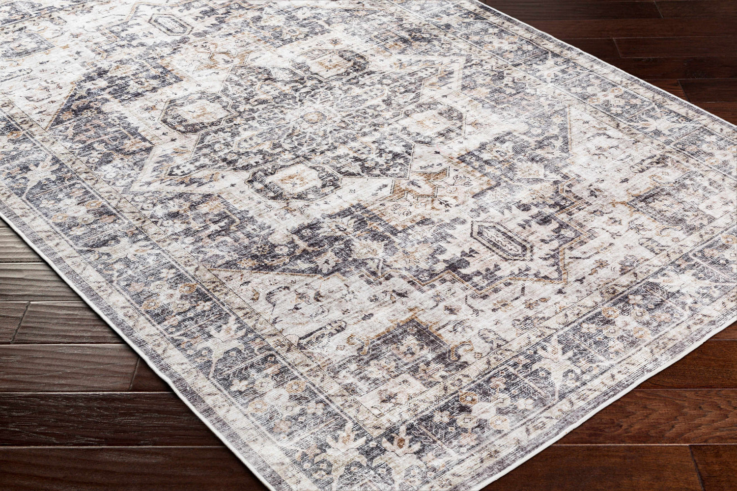 Close-up of the Bevin Washable Area Rug. Farmhouse style rug in dark brown, gray, and taupe on dark wood flooring. Corner