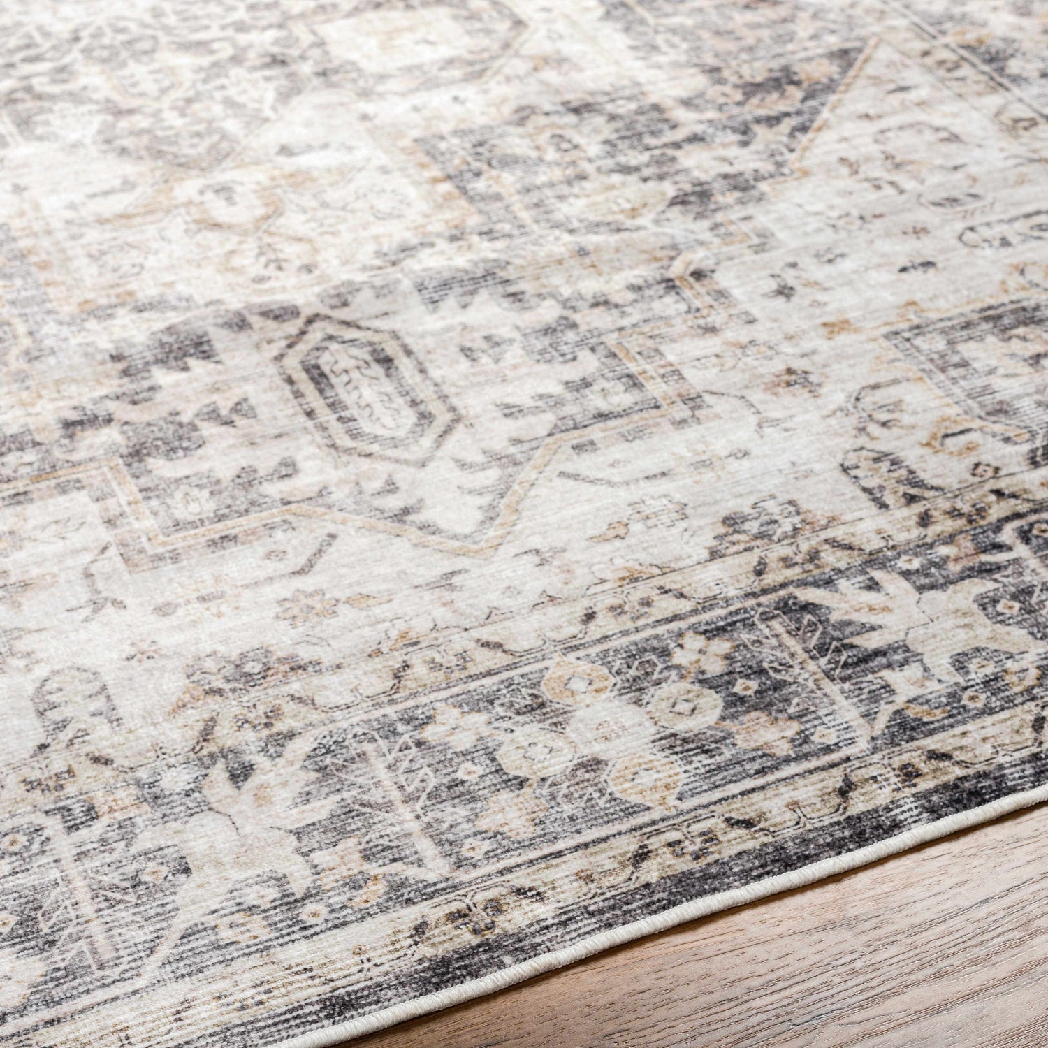 Close-up of the Bevin Washable Area Rug, showcasing its traditional pattern, dark gray, taupe, and natural gray colors. Texture