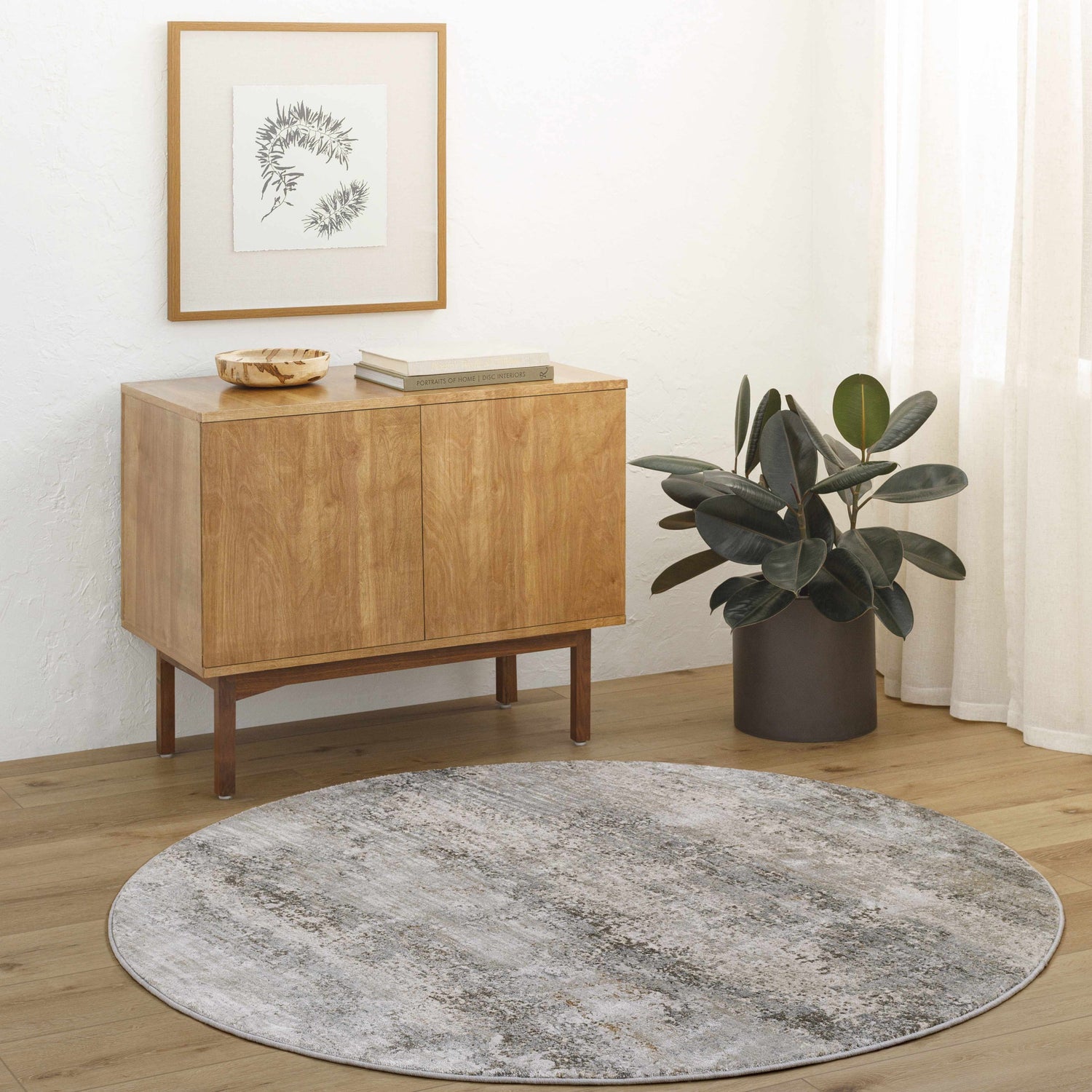 Minimalist room scene with a round Bowdoinham rug in charcoal, sage, and gray tones under a wood cabinet. Roomscene-Round