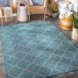 Outdoor patio scene with Unique Outdoor Trellis Area Rug, Teal. Wicker chairs, stone floor, and baskets create a cozy space. Roomscene-Rectangle