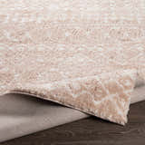 Close-up of the Blush Plush Area Rug showing its soft, textured pile and blush and cream colors. Fold