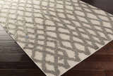 Close-up of Clare Area Carpet. Hand-woven wool shag rug in charcoal and medium gray with geometric lattice design. Corner