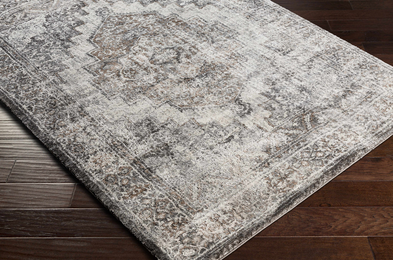 Close-up of the Manaring Charcoal Luxe Thick Area Rug showing its traditional pattern and soft texture on dark wood flooring. Corner
