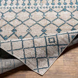 Close-up of Cabognon Washable Area Rug. Geometric pattern in blue, beige, and gray. Machine woven texture. Farmhouse style. Fold
