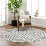 Living room scene with a round Cabognon Washable Area Rug in light beige and blue under a gray chair with a throw and pillow. Roomscene-Round