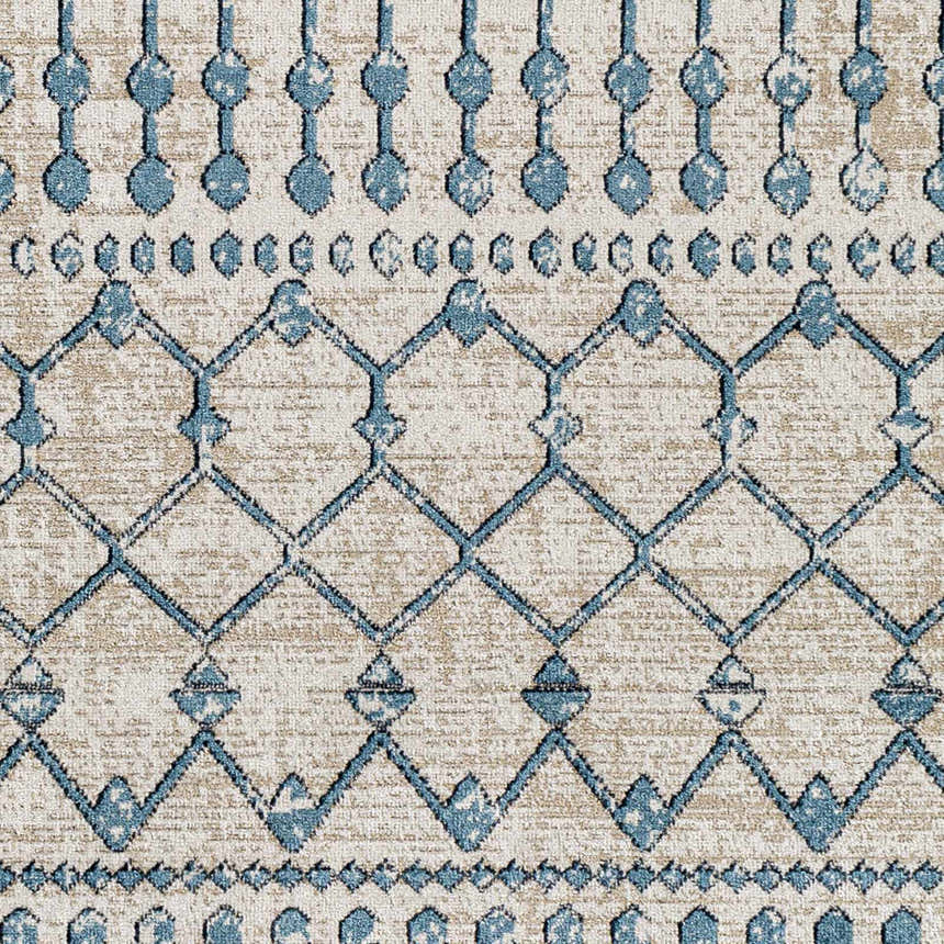 Close-up of the Cabognon Washable Area Rug. Features a blue geometric pattern on a light beige background. Texture