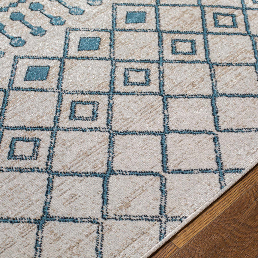 Close-up of Cabognon Washable Area Rug with a geometric pattern in blue, ink blue, light beige, and light gray on wood floor. Texture