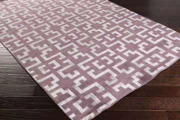 Close-up of Calhoun Area Carpet. Mauve rug with a modern geometric pattern on dark wood floors. Corner