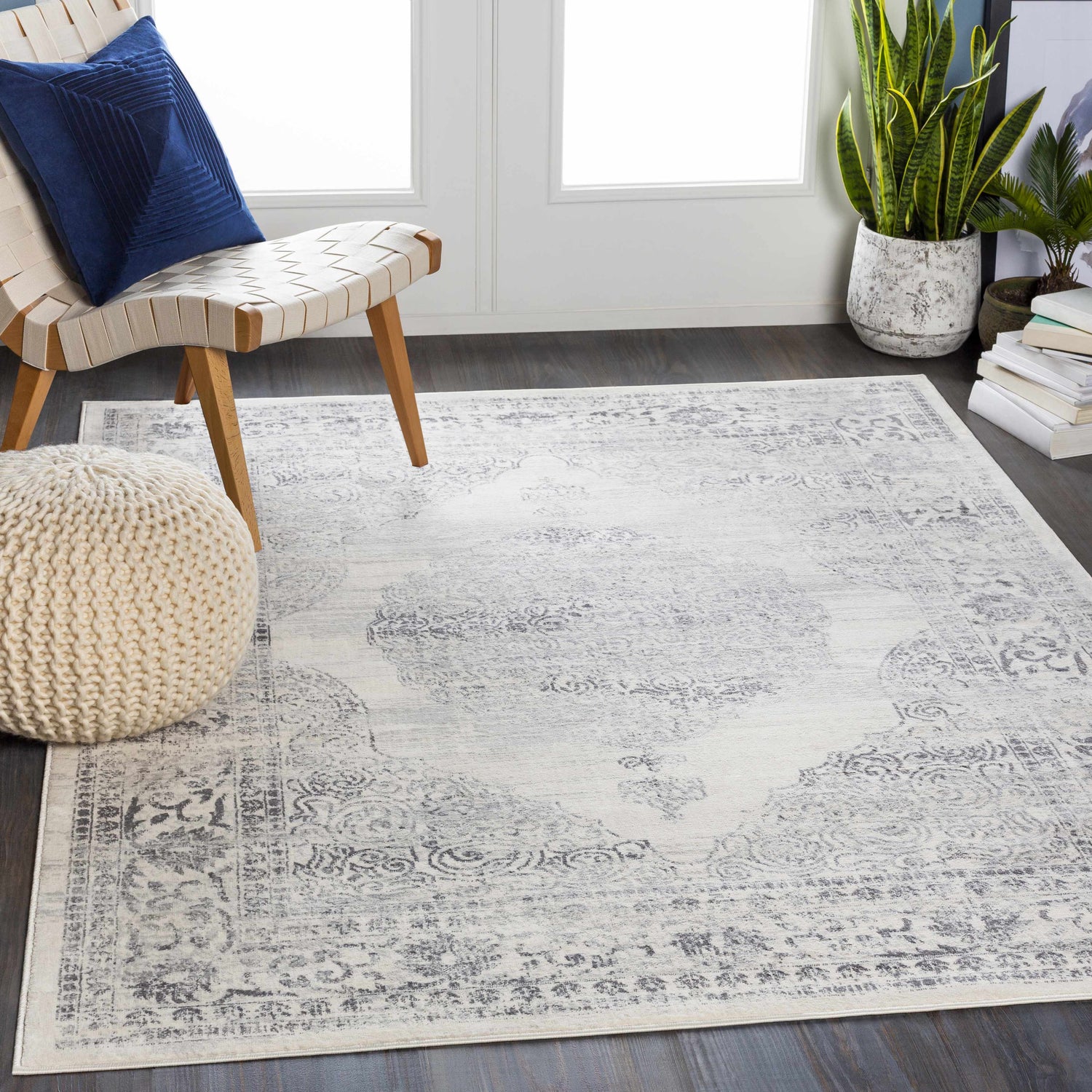Living room scene with charcoal and gray Caloundra Area Rug, chair with blue pillow, and knit pouf. Roomscene-Rectangle