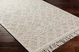 Close up of Cameo Scandi Wool Rug in bone on dark wood floor. Geometric pattern and fringe detail visible. Farmhouse style. Corner