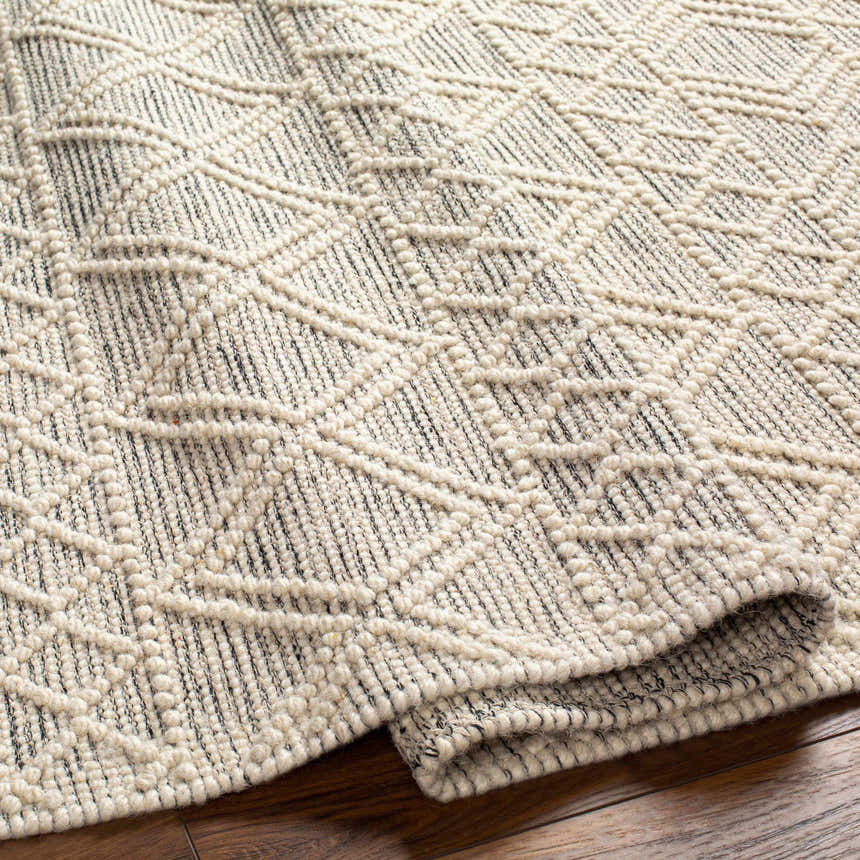 Close up of the Cameo Scandi Wool Rug showing bone and gray geometric pattern and hand woven texture. Fold
