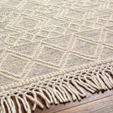 Close-up of Cameo Scandi Wool Rug in bone. Features geometric pattern, hand-woven texture, and knotted fringe detail. Texture
