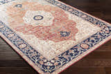 Close-up of the Camperdown Area Rug, a traditional rug in burnt orange, cream, and dark blue on a dark wood floor. Corner