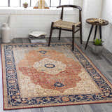 Living room scene with burnt orange Camperdown Area Rug, dark blue floral border, wood chair, and white brick wall. Roomscene-Rectangle