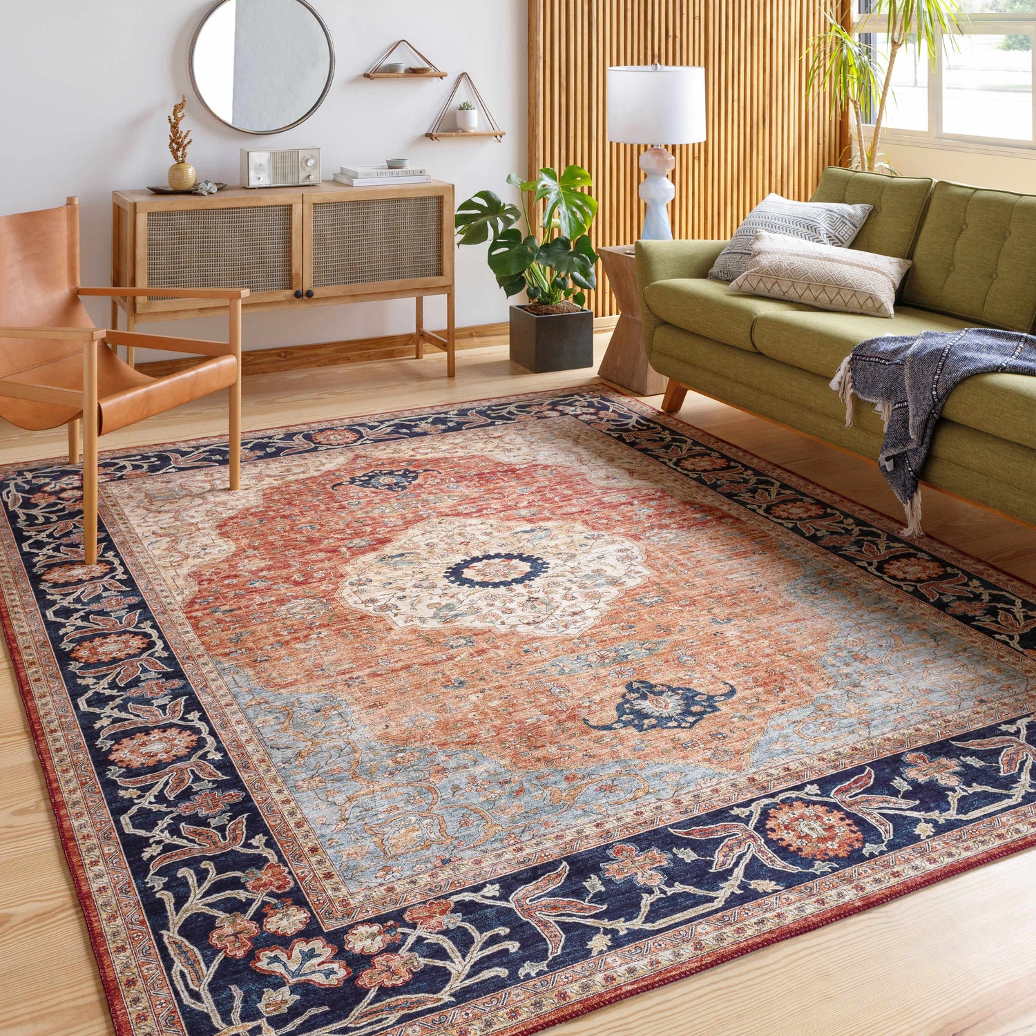 Living room scene with green sofa and Camperdown Area Rug in burnt orange, cream, and dark blue. Roomscene-Rectangle