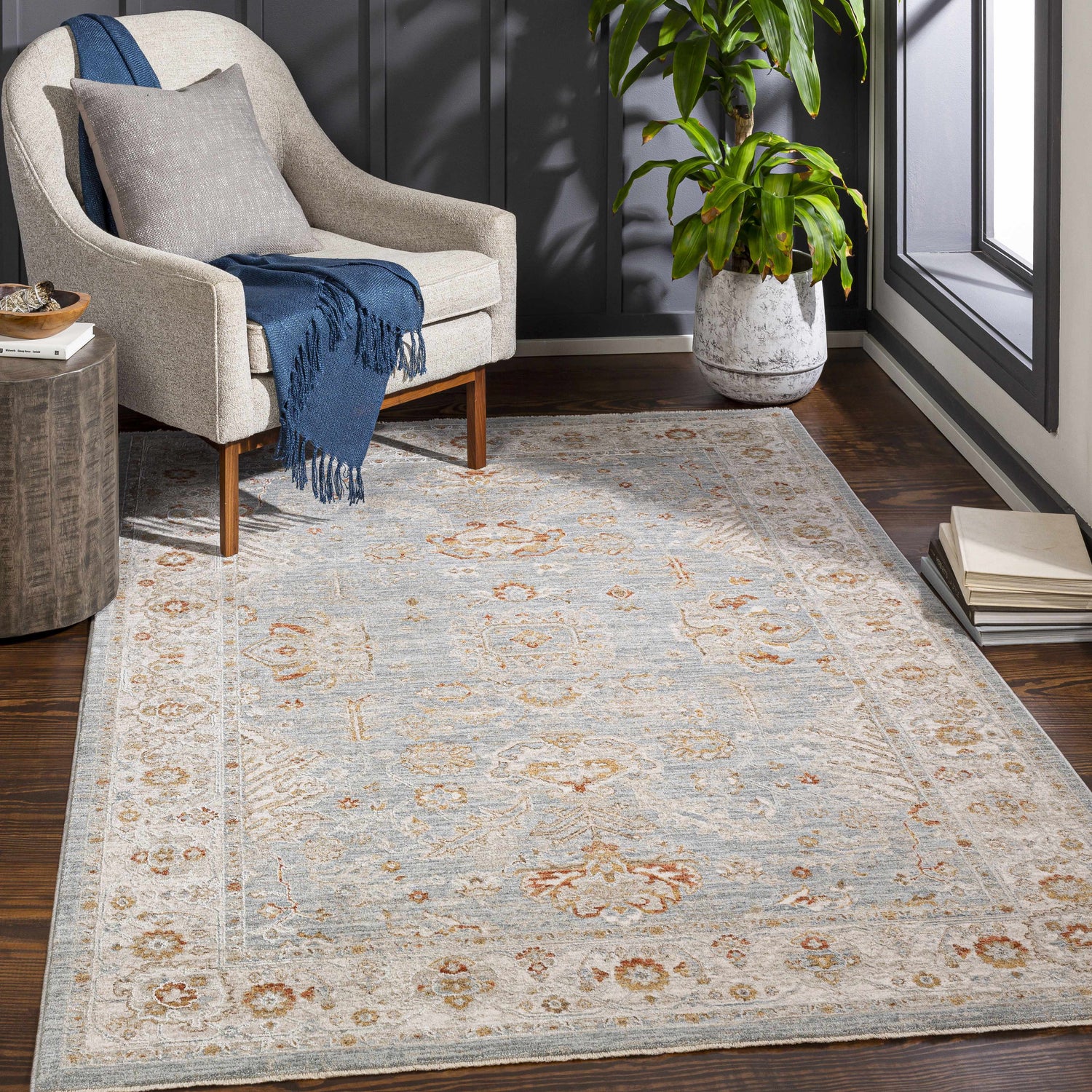 Living room scene with a light beige chair and Camrose Thick Luxe Statement Rug in light blue and brick red. Roomscene-Rectangle