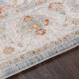 Close-up of the Camrose rug showing its light beige base with brick red, denim, and mustard floral accents. Texture