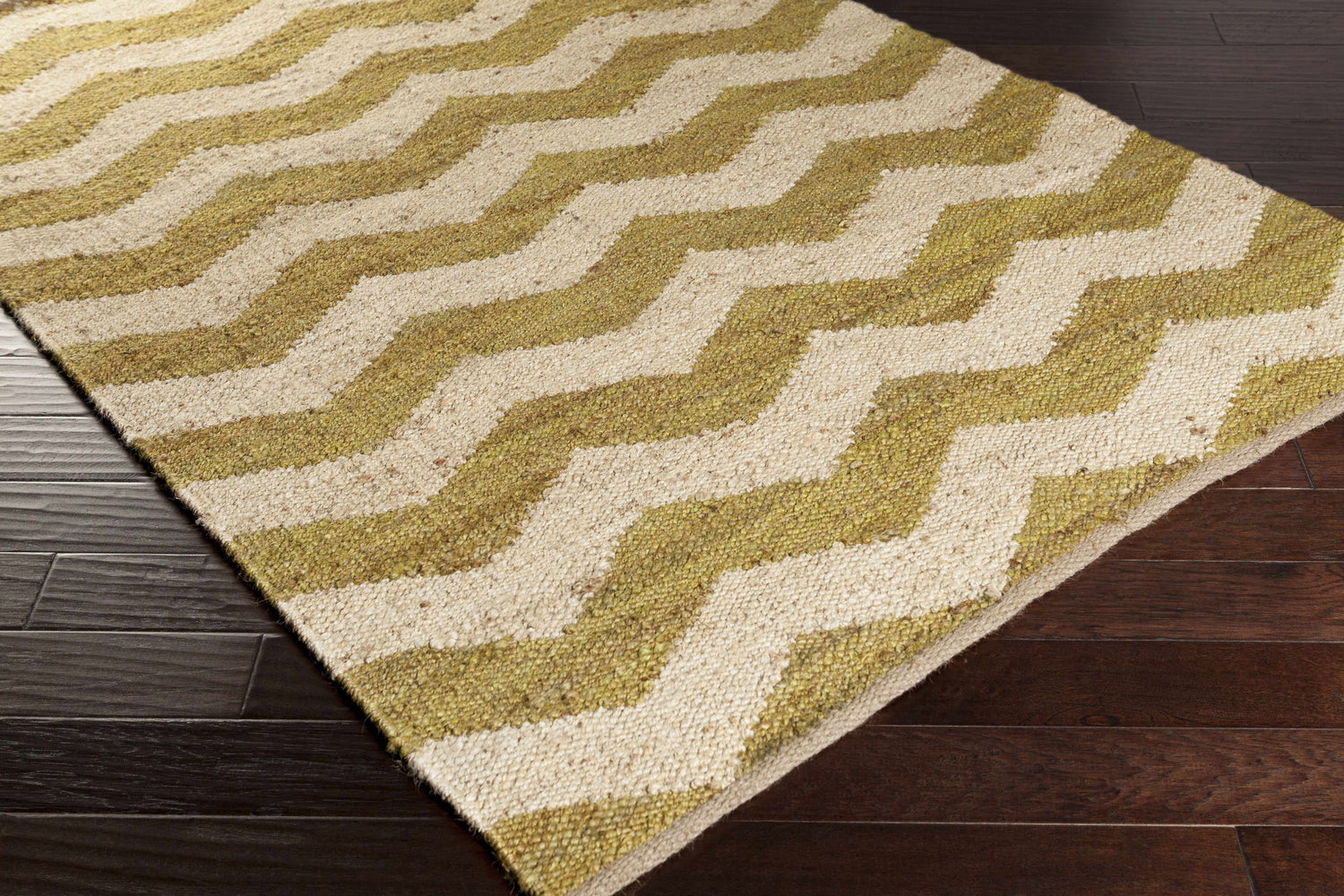 Close-up of a hand-woven Cardigan Jute Carpet. Beige and lime green zigzags create a farmhouse-style pattern. Natural fiber texture. Corner