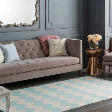 Living room scene with a Caswell Area Rug in ice blue and ivory, styled with a taupe sofa and gray walls. Roomscene-Rectangle