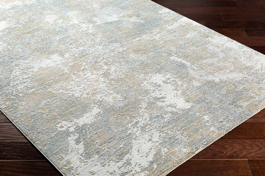 Close-up of Cady Thick Luxe Area Rug on dark wood floor. Abstract design in cloud gray, light gray, and medium brown. Corner