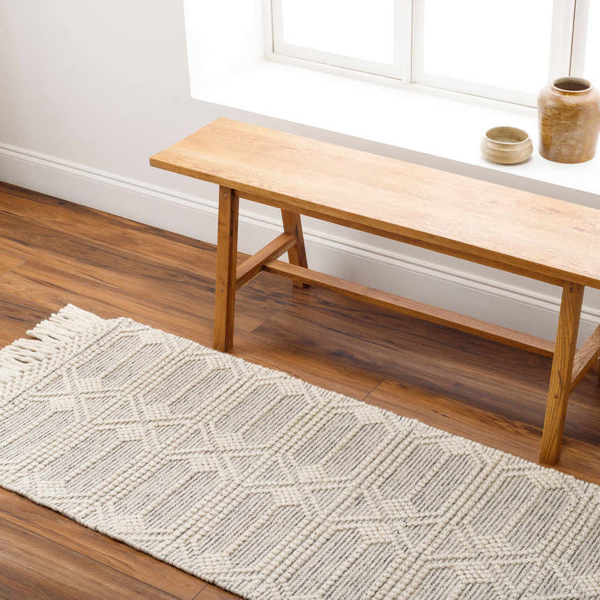 Hallway scene with a Chars Wool Rug. Bone rug with geometric pattern and tassels under a wood bench. Roomscene-Runner