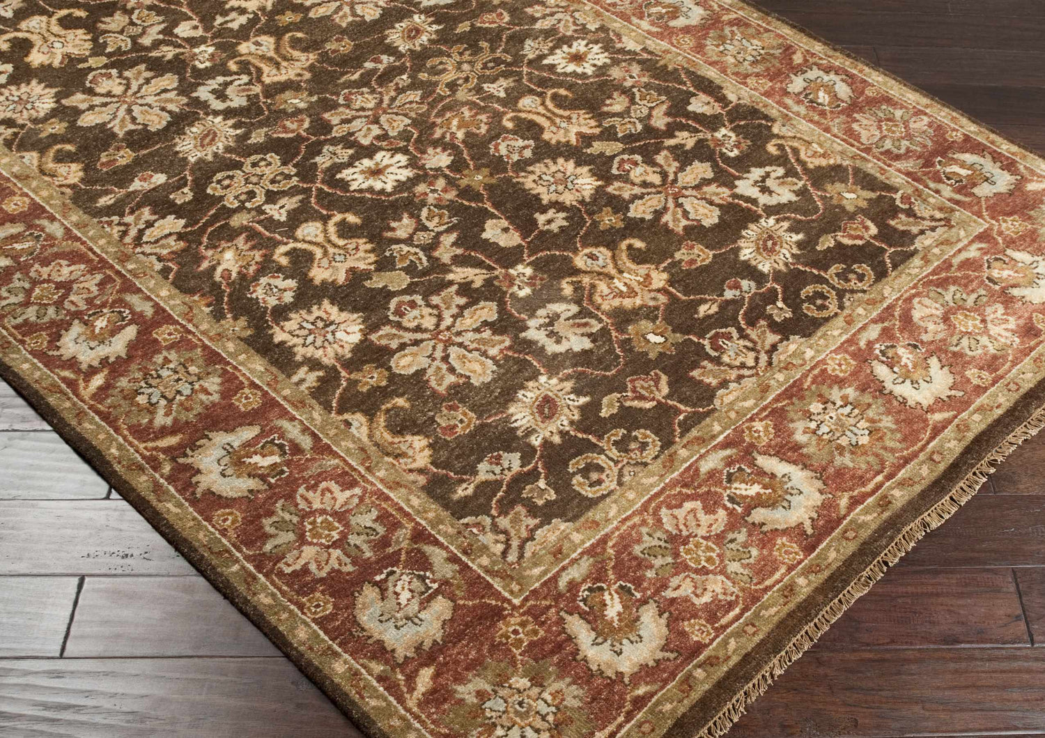 Close-up of the hand-knotted Chinle Premium Wool Area Carpet. Features a traditional floral pattern in brick red, brown, and beige tones. Corner