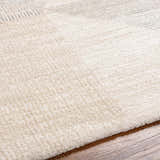 Close-up of the Chizu Geometric Neutral Luxe Rug showing bone and gray tones and soft, textured pile on hardwood floor. Texture
