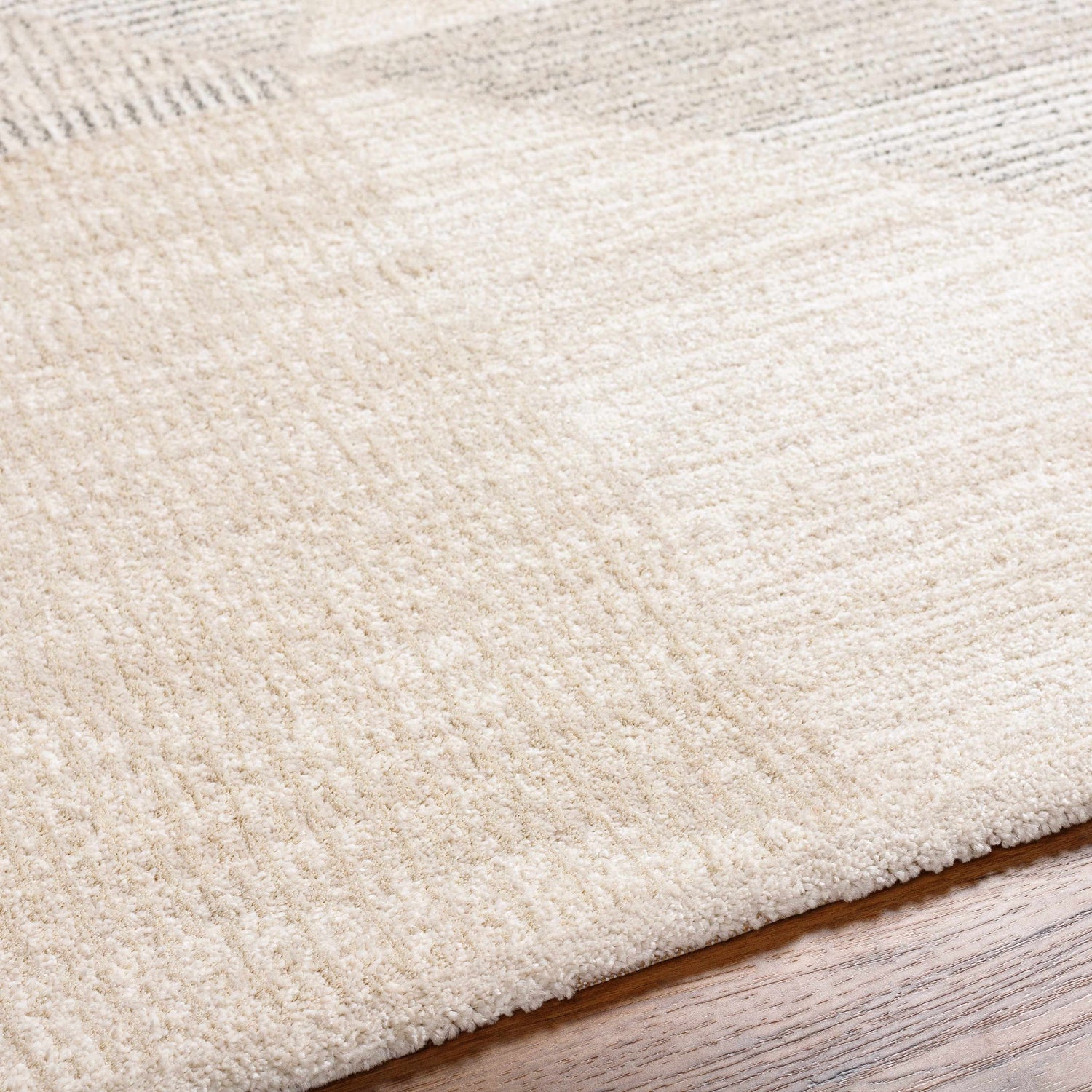Close-up of the Chizu Geometric Neutral Luxe Rug showing bone and gray tones and soft, textured pile on hardwood floor. Texture