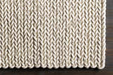 Close-up of the cream Christoval Area Rug showing its hand woven, braided wool texture and pattern. Corner
