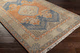 Close-up of the Charmhaven Area Rug. Hand-knotted wool rug with blue, brown, burnt orange, and tan oriental-inspired design. Corner