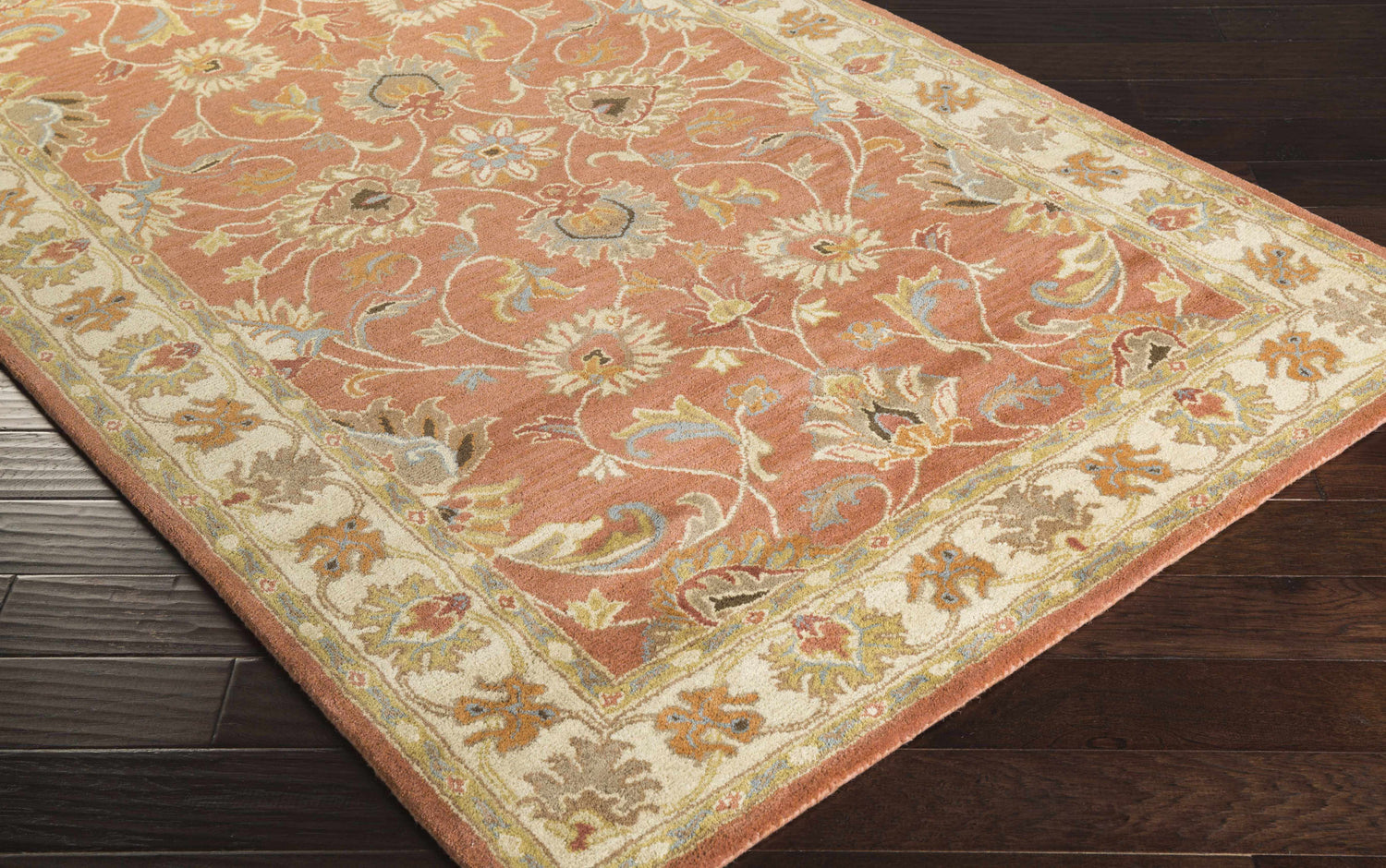 Close-up of the Caesar Hand Tufted Burnt Orange 1124 Wool Carpet. Features floral pattern in brick red, brown, and blue hues. Corner