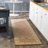 Kitchen scene with Caesar Hand Tufted Burnt Orange Wool Runner Rug. Features white cabinets, wood floors, and a gray kitchen island. Roomscene-Runner
