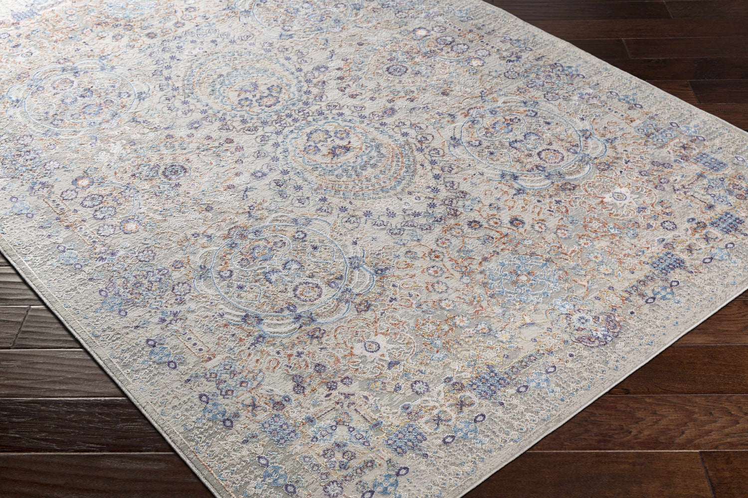 Close-up of Aisha Abstract Premium Sheen Viscose Rug. Features blue, orange, and purple floral pattern on a taupe background. Corner