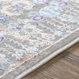 Close-up of the Aisha Abstract Premium Sheen Viscose Rug. Features blue, purple, and peach floral accents on a gray background. Texture