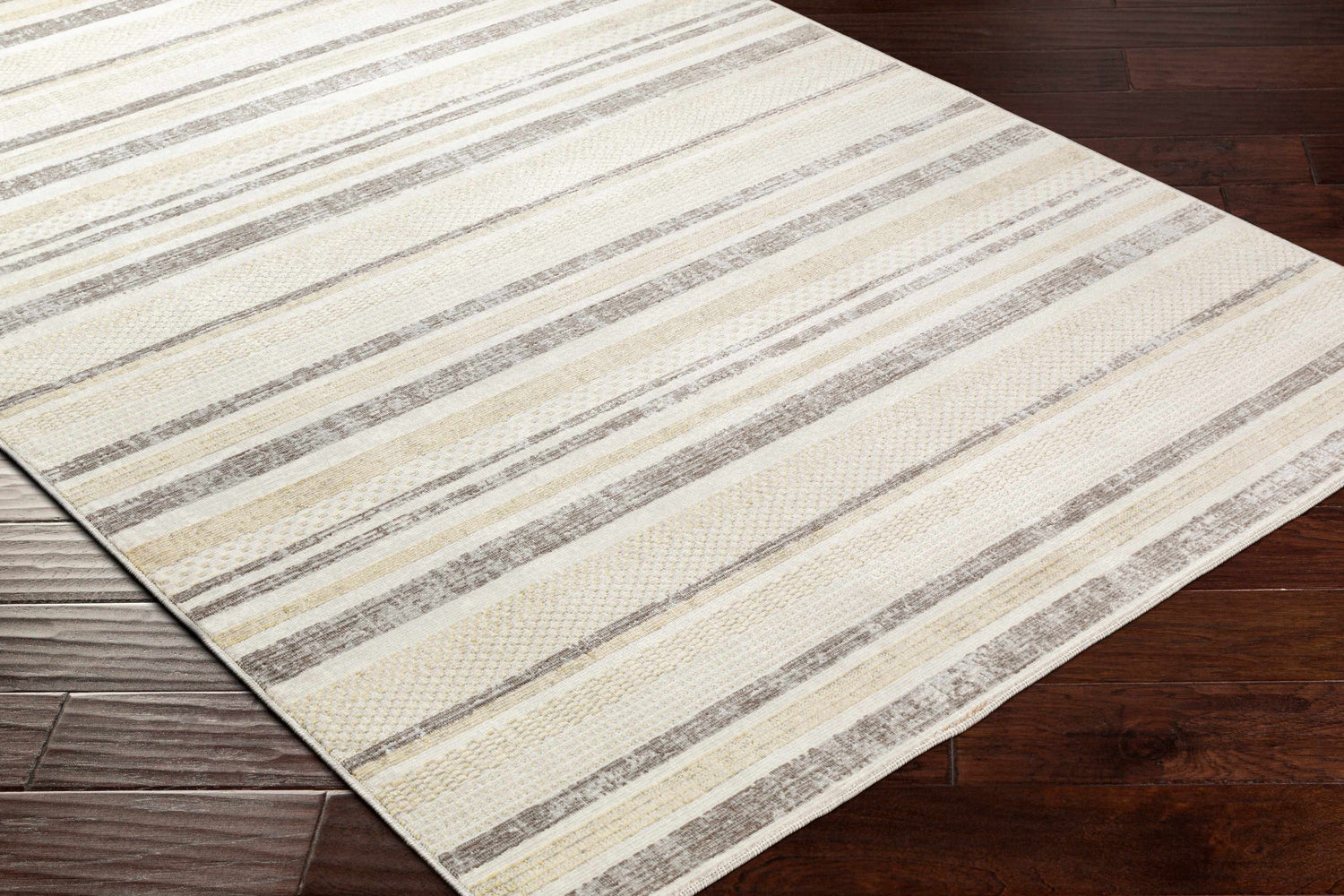 Close-up of Chato Area Rug showing bone, gray, nutmeg, and white thatch stripes on dark wood floor. Geometric, coastal style. Corner