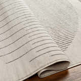 Close-up of the Chet Area Rug showing its gray geometric line pattern and soft, textured weave. Fold
