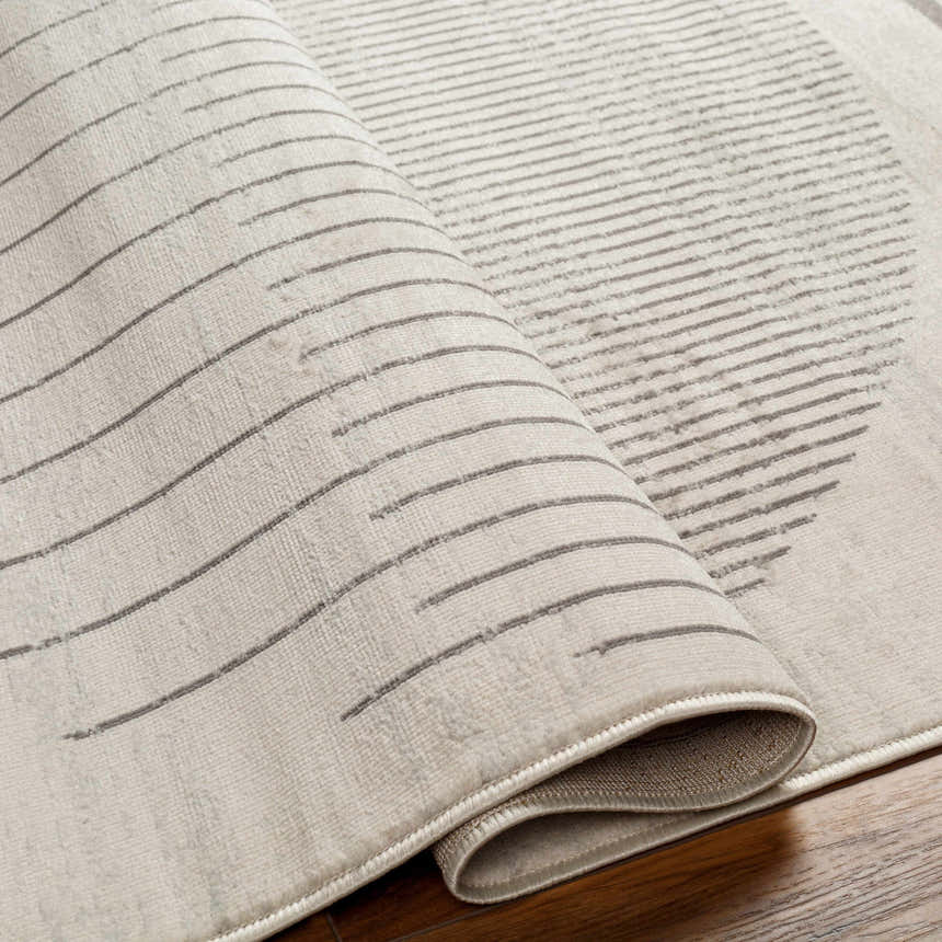 Close-up of the Chet Area Rug showing its gray geometric line pattern and soft, textured weave. Fold