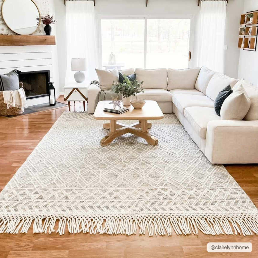 Living room scene with a cream sectional and the neutral Ossun Wool Rug with Tassels, creating a cozy farmhouse vibe. Roomscene-Rectangle